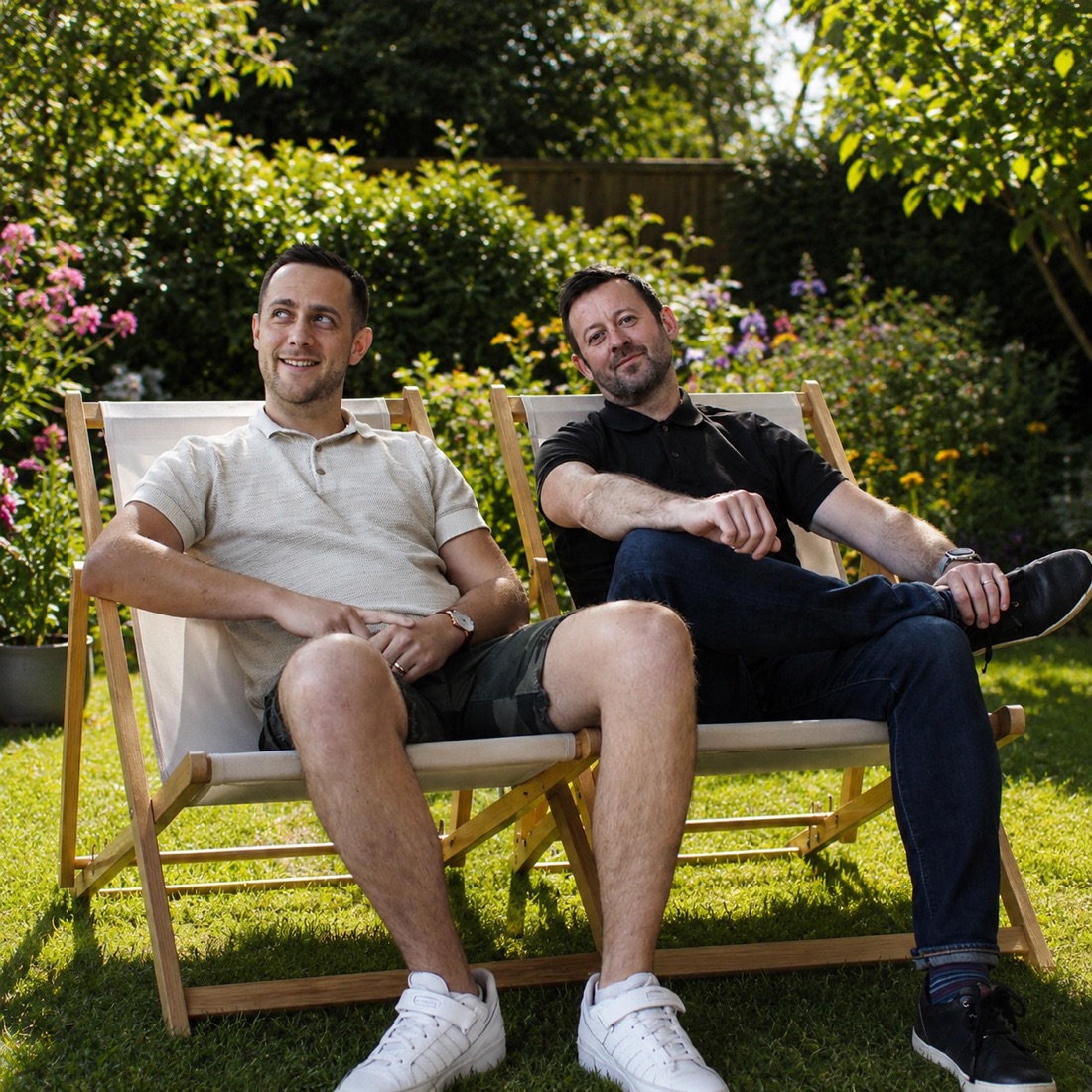 The two Gardn founders in deckchairs in a summer garden, borders in full flower behind them.